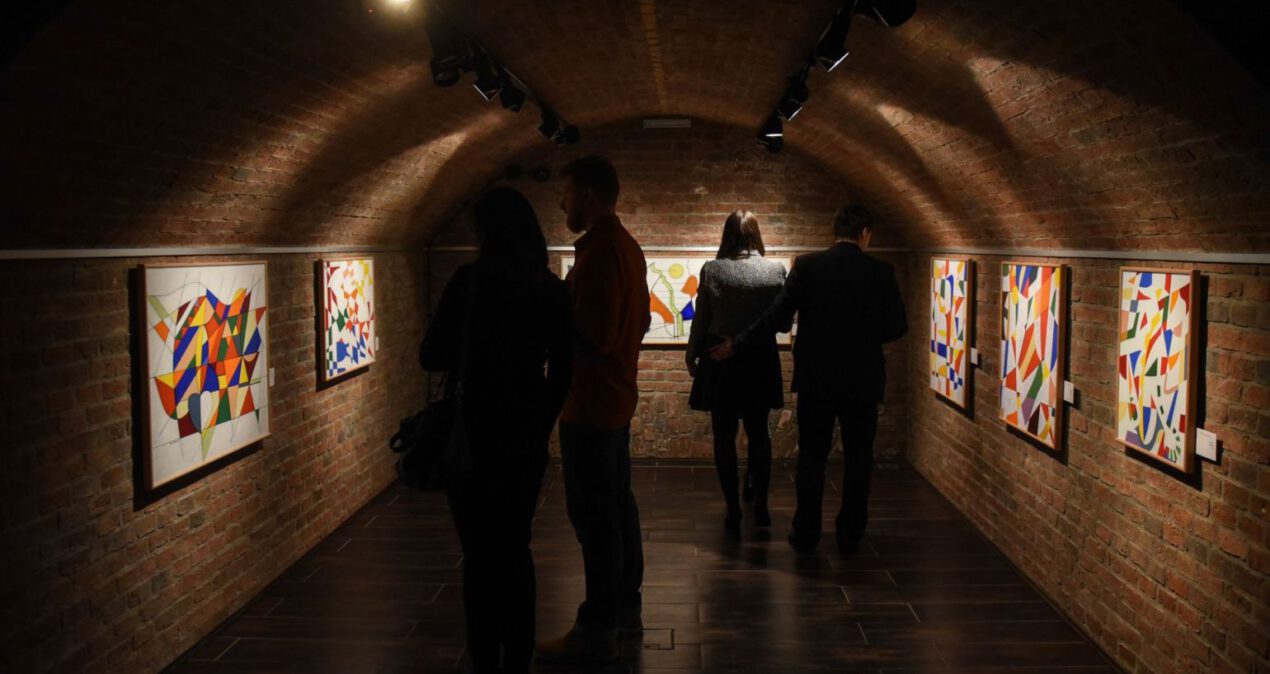 Wnętrze sali wystawowej z abstrakcyjnymi obrazami w żywych kolorach
