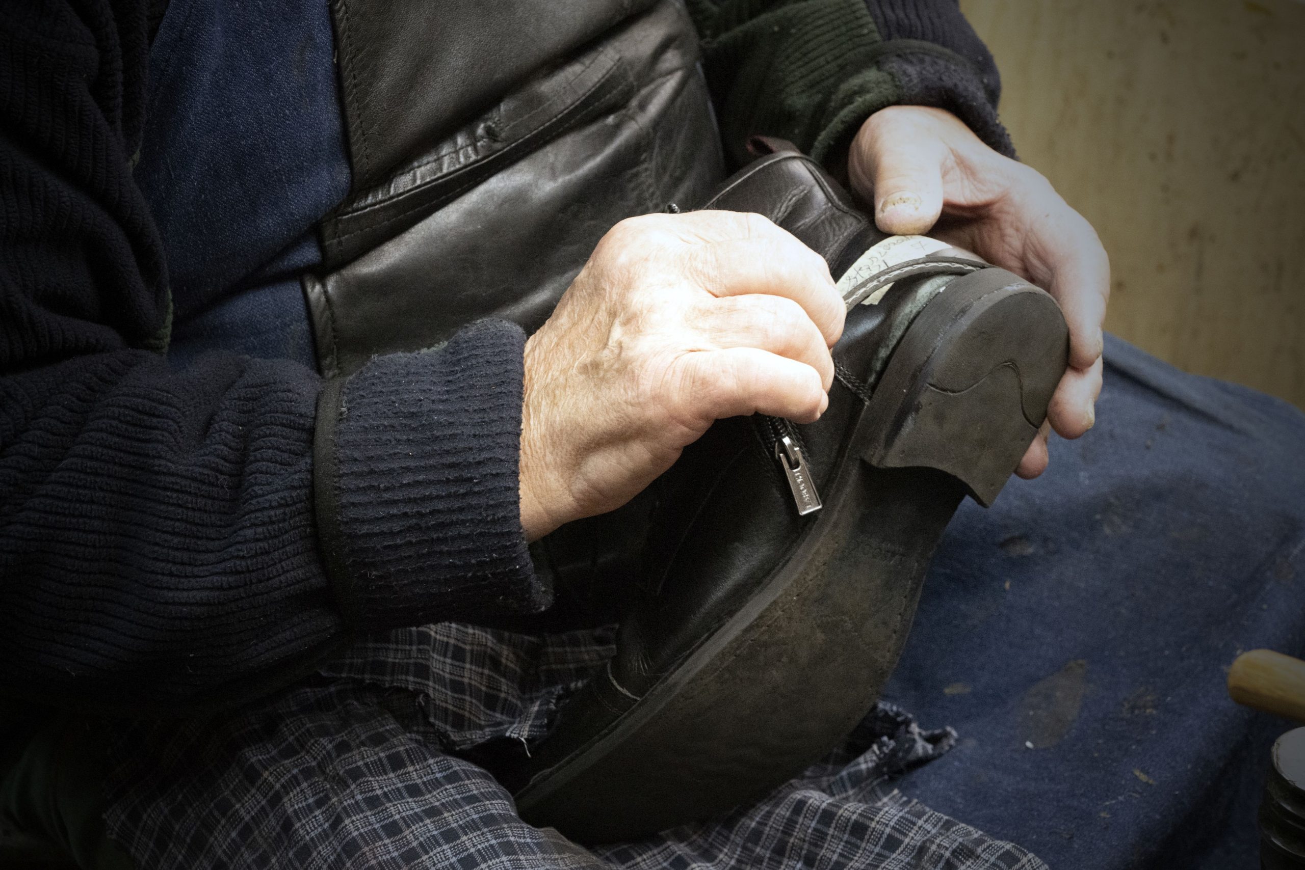 Widok na dłonie mężczyzny, który naprawia buty