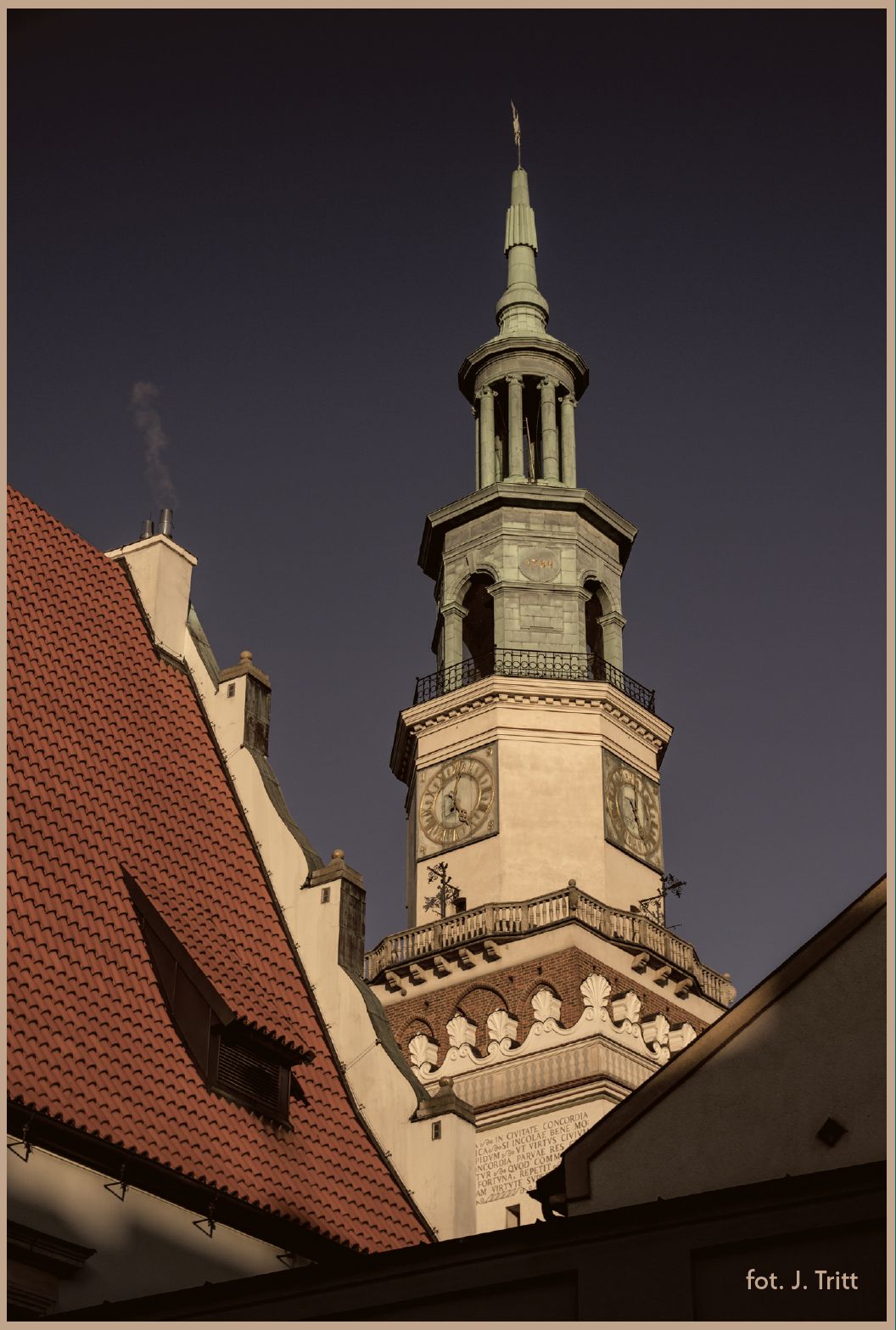 Czubek wieży ratusza wystaje nad okoliczne dachy. Widać białą ośbiokątną część z zegarami, a nad nią ozdobny miedziany czubek.