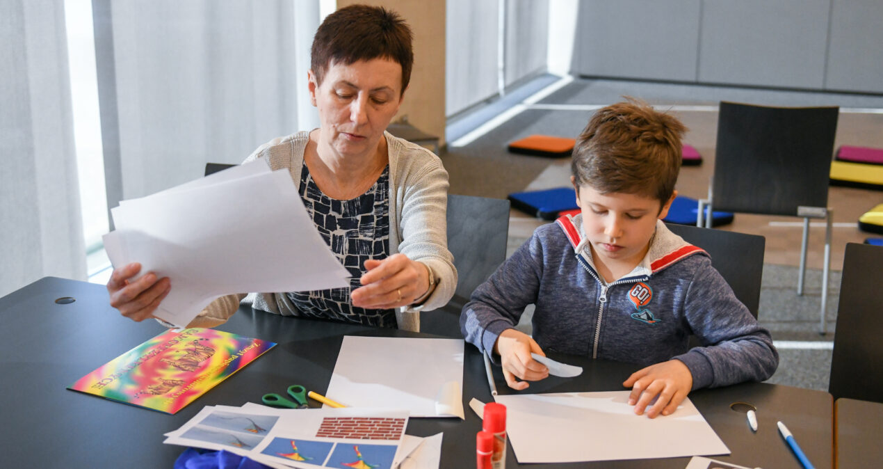 Kobieta i chłopiec wspólnie wykonują pracę plastyczną